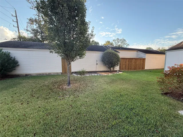 a backyard of a house with table and chairs plants and large tree
