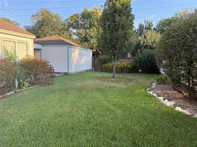 a backyard of a house with plants and large tree