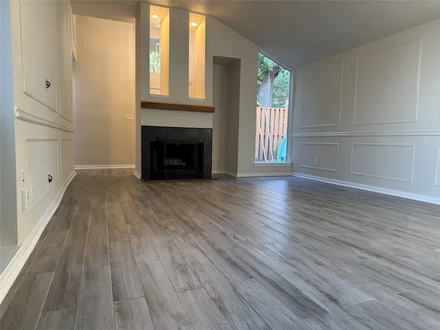 a view of an empty room with wooden floor and a window