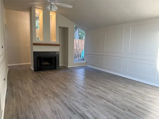 an empty room with wooden floor fireplace and windows