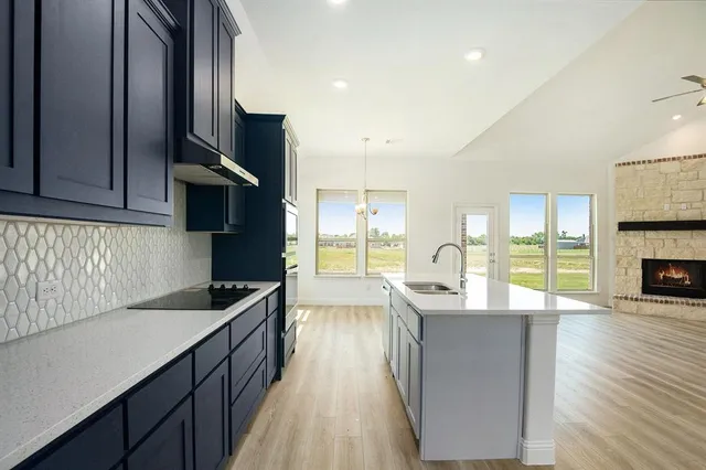 a kitchen with stainless steel appliances granite countertop a refrigerator a sink dishwasher a stove and white countertops with wooden floor