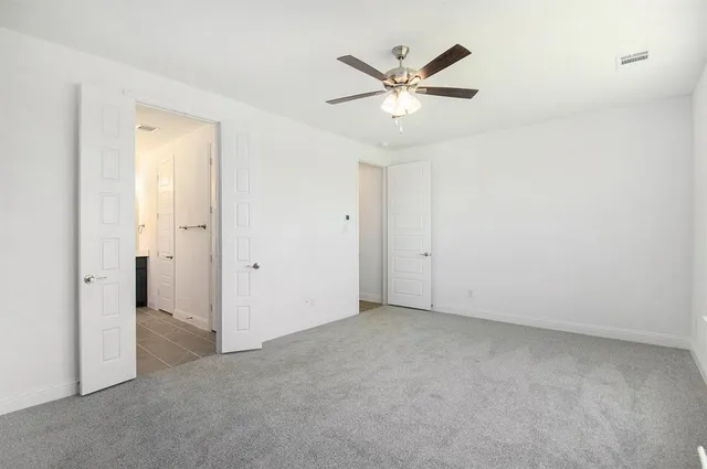 an empty room with a chandelier fan and a window