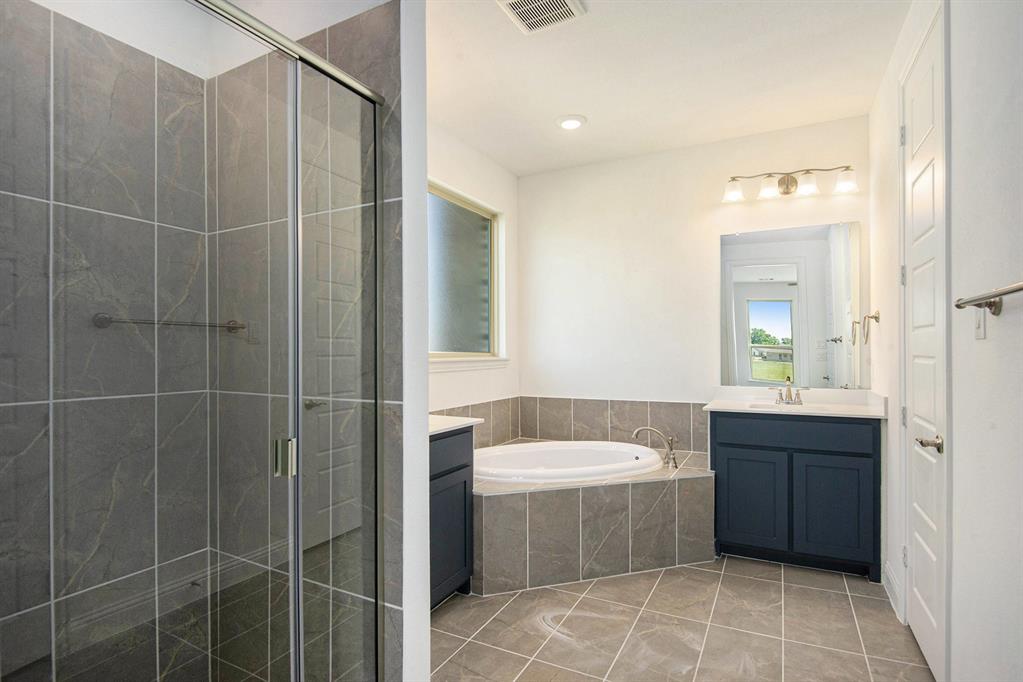 6033 Mango Drive Sanger, TX 76266 - Photo 19 of 29 a bathroom with a bathtub sink vanity and toilet