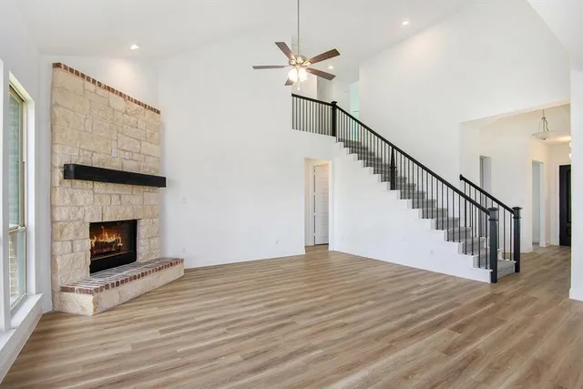 a view of an empty room with wooden floor a fireplace and a window