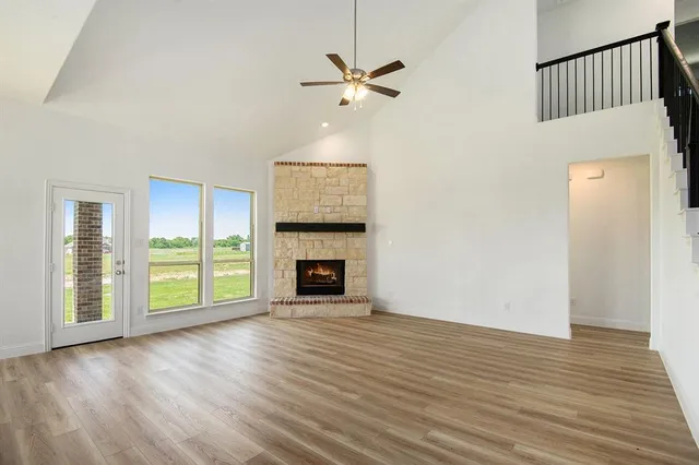 an empty room with wooden floor a fireplace and windows