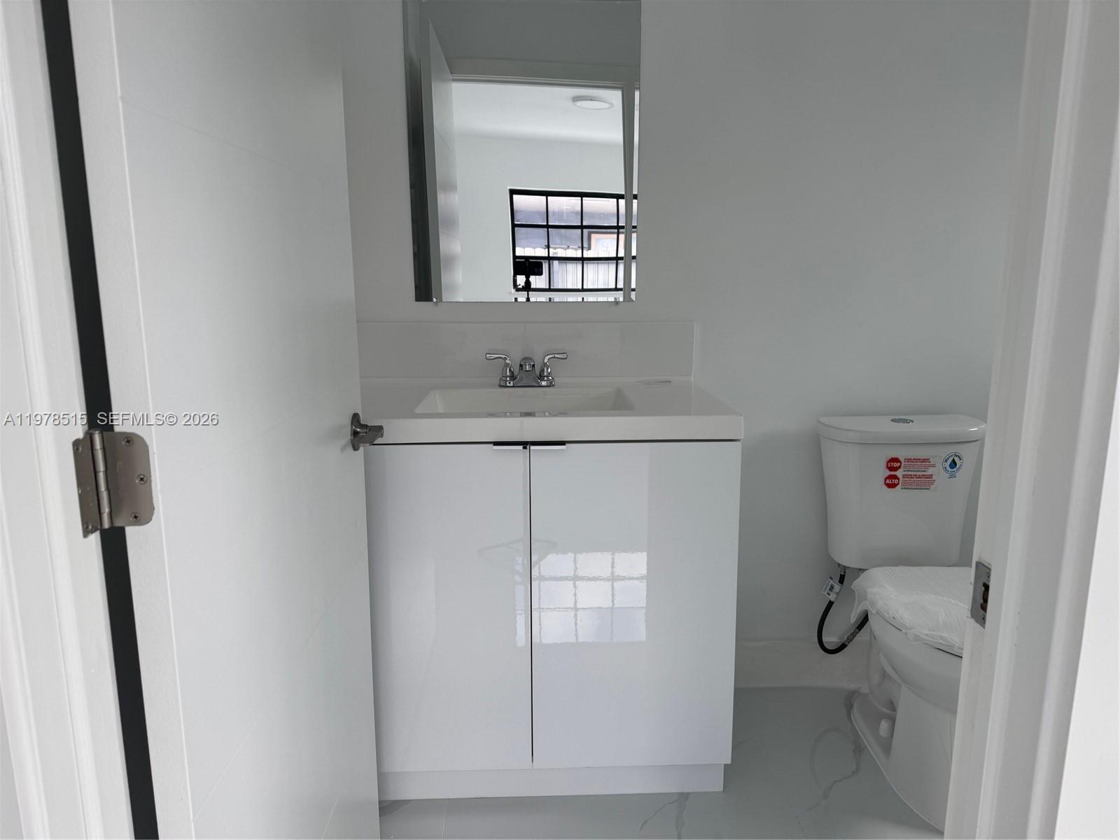 2682 West 70th Place Hialeah, FL 33016 - Photo 6 of 16 a bathroom with a granite countertop toilet a sink and mirror