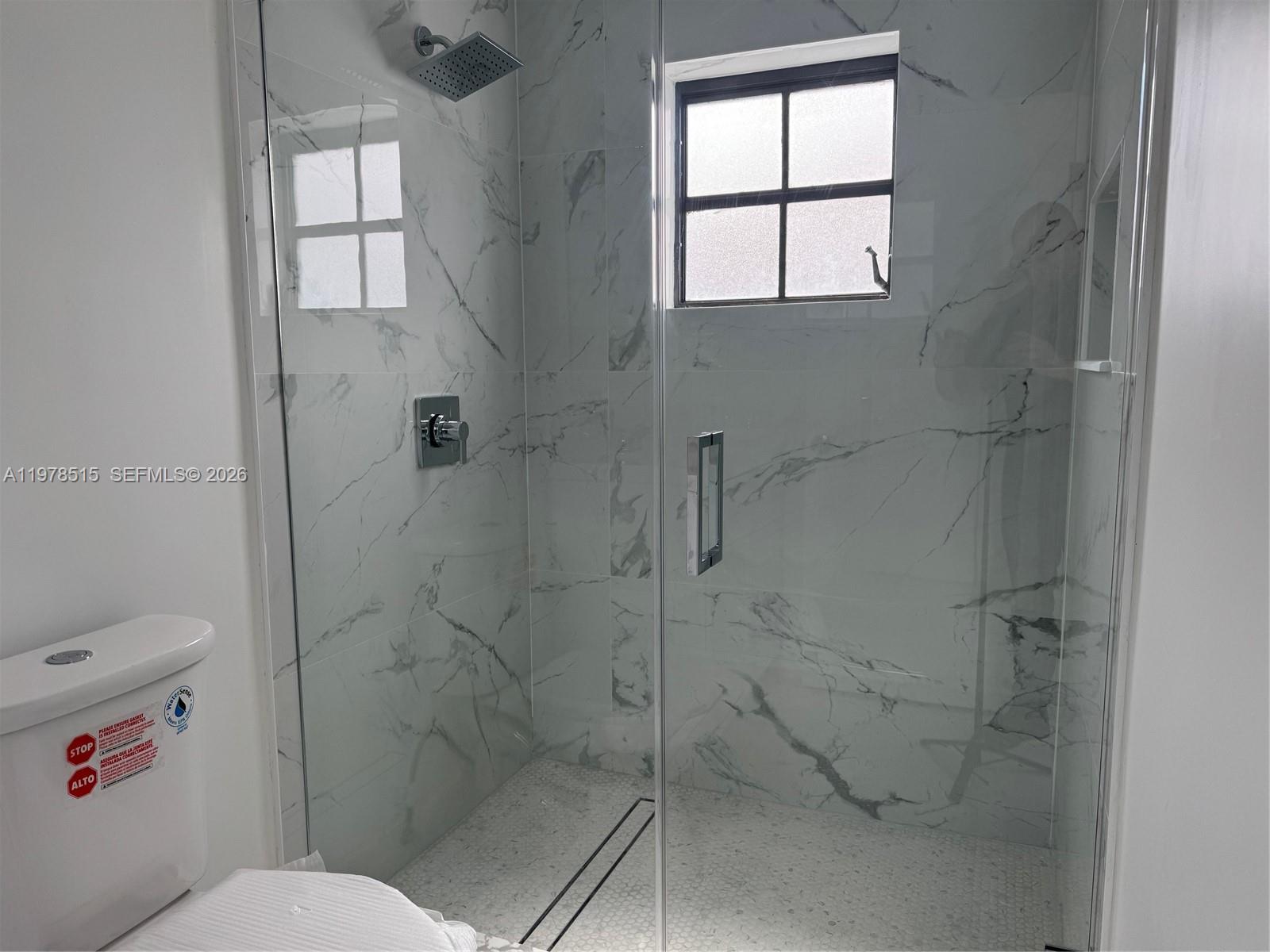 2682 West 70th Place Hialeah, FL 33016 - Photo 8 of 16 a bathroom with a window toilet and shower
