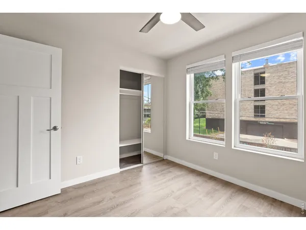a view of an empty room with a window and wooden floor