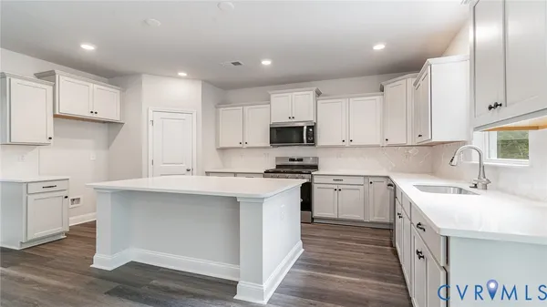a kitchen with a sink stove cabinets and wooden floor