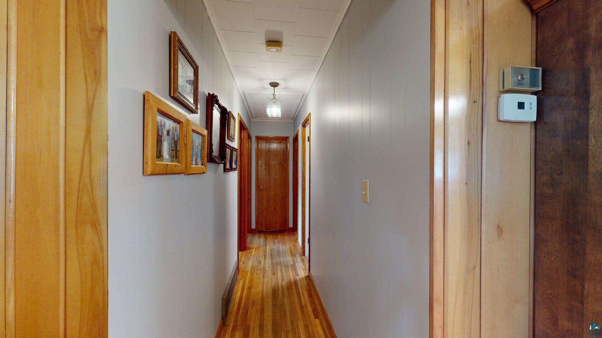 10614 Moose Lake Road Orr, MN 55771 - Photo 20 of 44 Hallway featuring wood-finish flooring, paneling with a natural wood finish, and painted wall surfaces