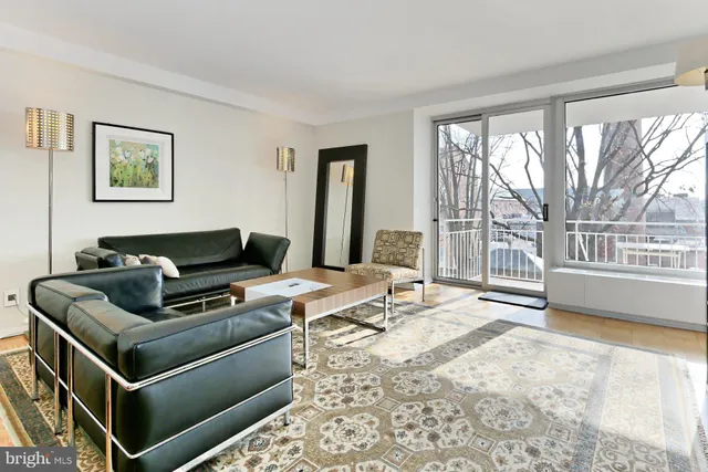 a living room with stainless steel appliances kitchen island granite countertop a sink and a stove top oven with wooden floor