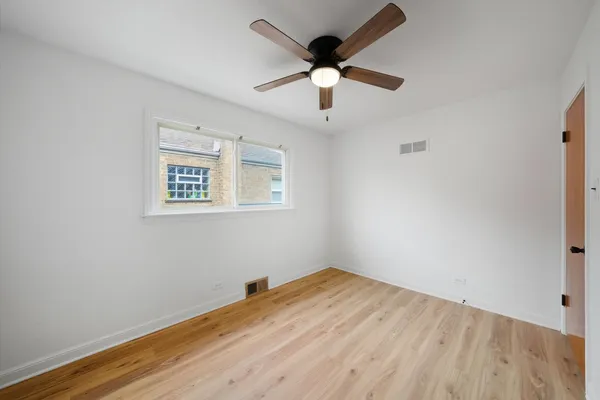a view of a room with wooden floor and a ceiling fan