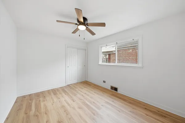 a view of empty room with wooden floor and ceiling fan