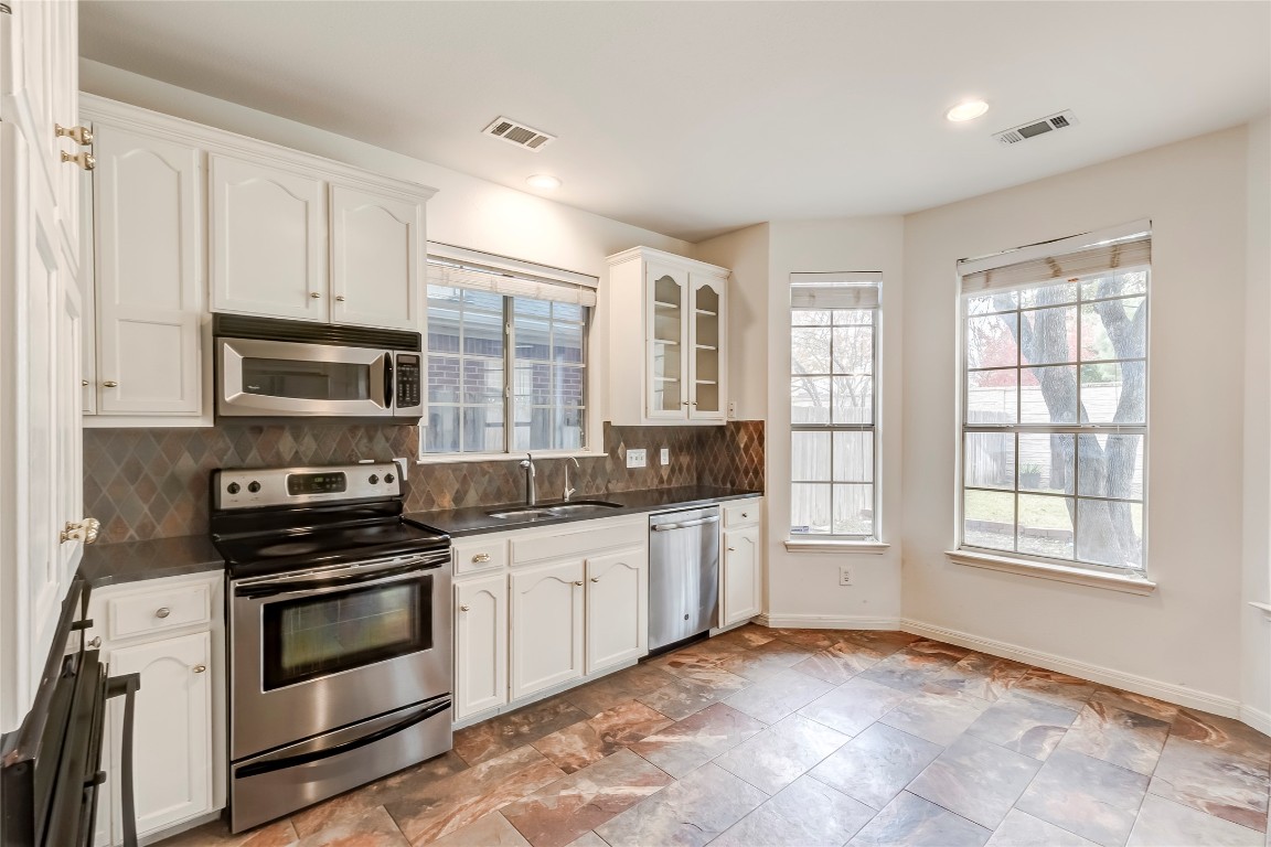 1901 Springwater Drive Round Rock, TX 78681 - Photo 16 of 36 a kitchen with granite countertop a stove a sink and a microwave