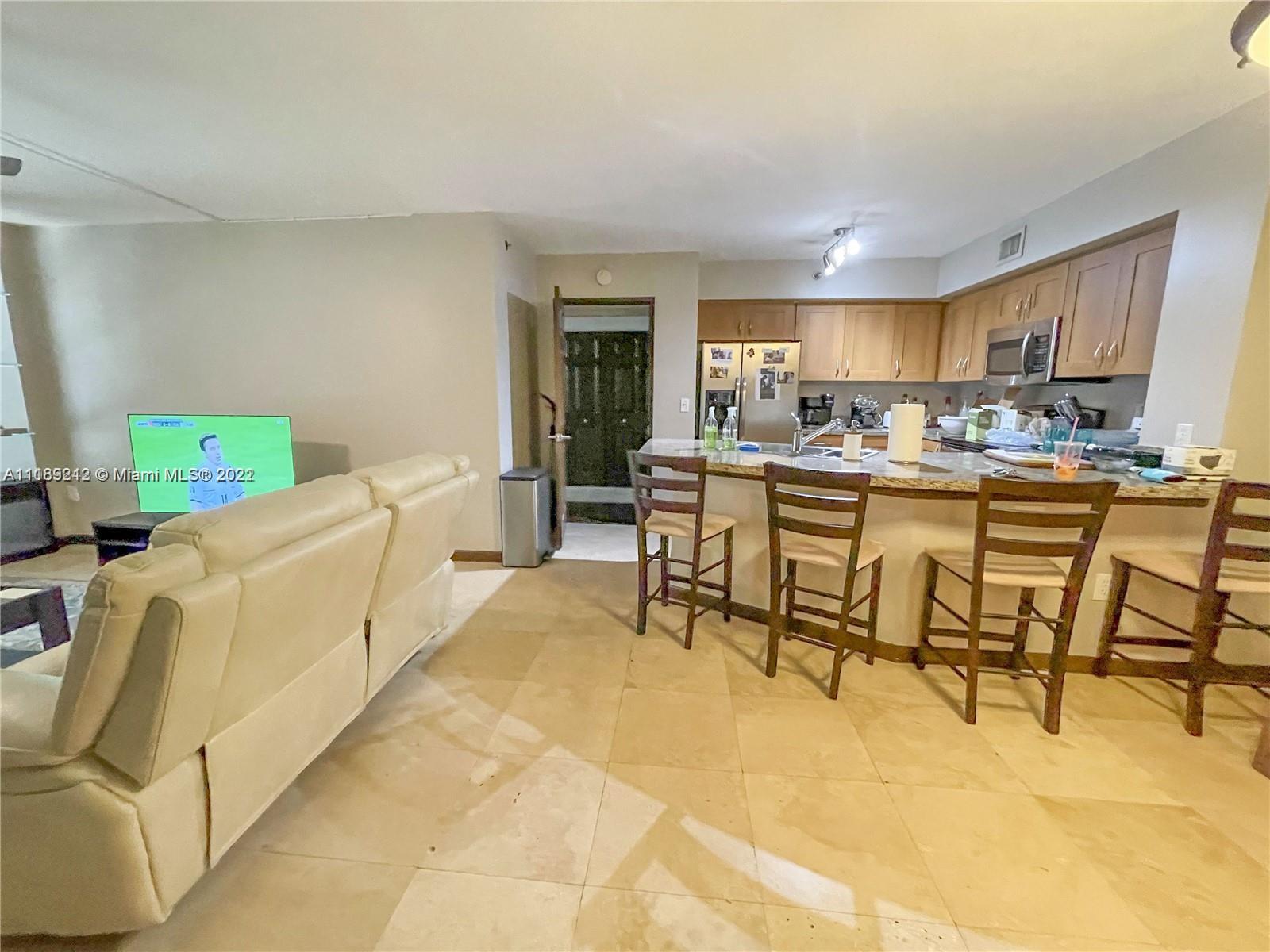 3153 Clint Moore Road, Unit 106 Boca Raton, FL 33496 - Photo 12 of 38 a living room with furniture a fireplace and a flat screen tv