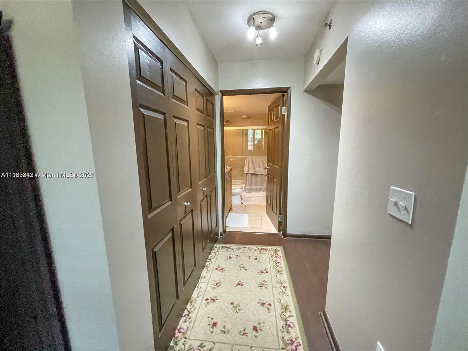 3153 Clint Moore Road, Unit 106 Boca Raton, FL 33496 - Photo 14 of 38 a view of hallway with wooden floor and a bathroom