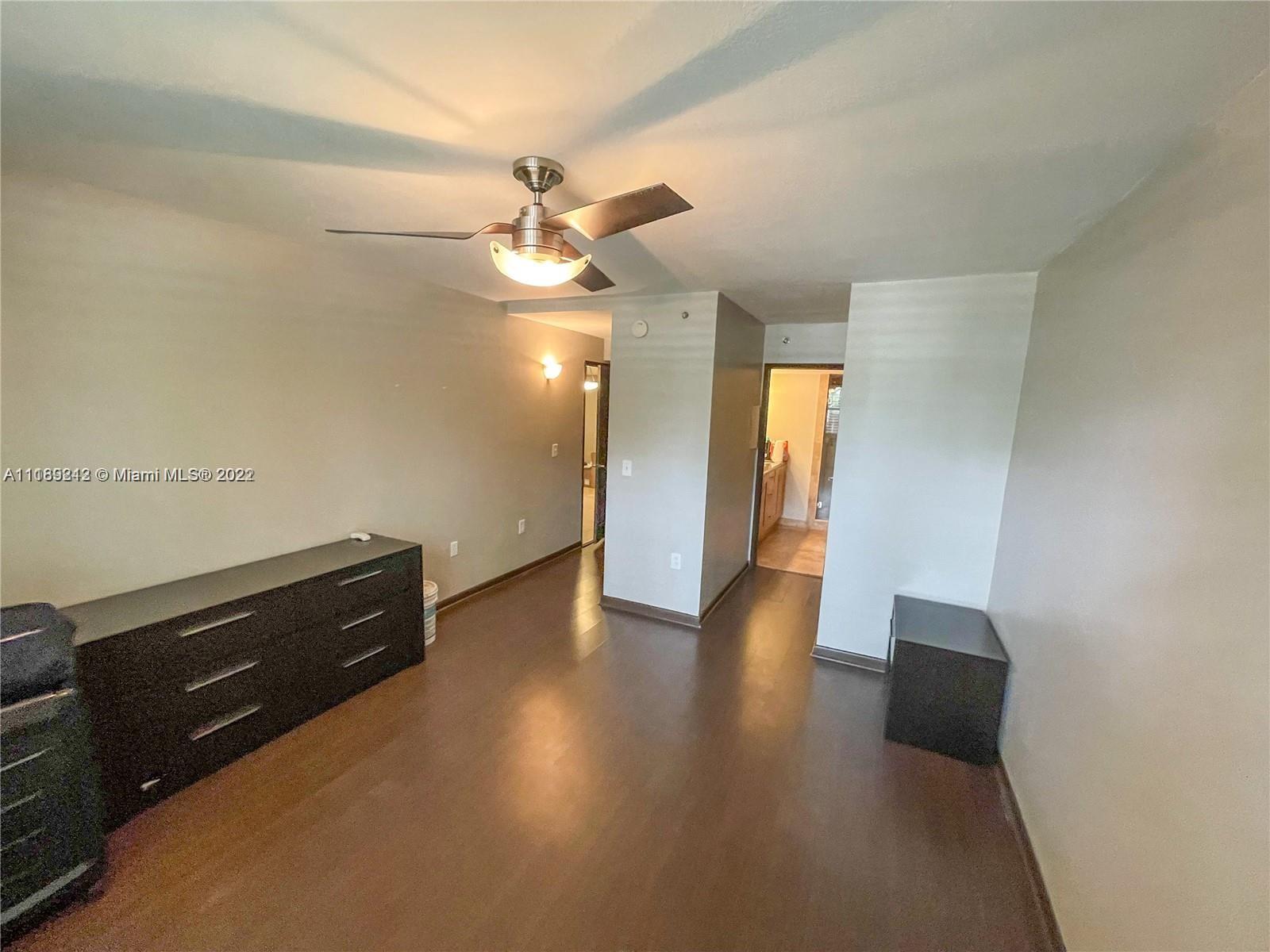 3153 Clint Moore Road, Unit 106 Boca Raton, FL 33496 - Photo 16 of 38 an empty room with wooden floor and cabinet