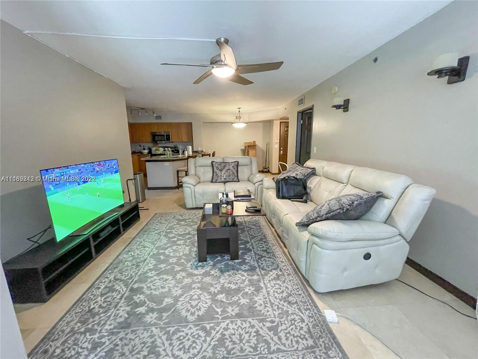 3153 Clint Moore Road, Unit 106 Boca Raton, FL 33496 - Photo 2 of 38 a living room with furniture and a flat screen tv