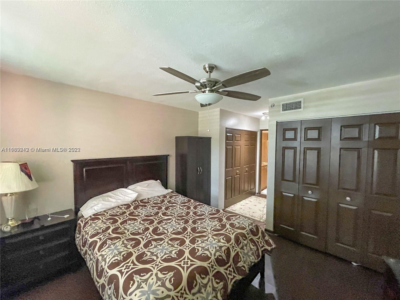 3153 Clint Moore Road, Unit 106 Boca Raton, FL 33496 - Photo 24 of 38 a bedroom with a large bed and a chandelier