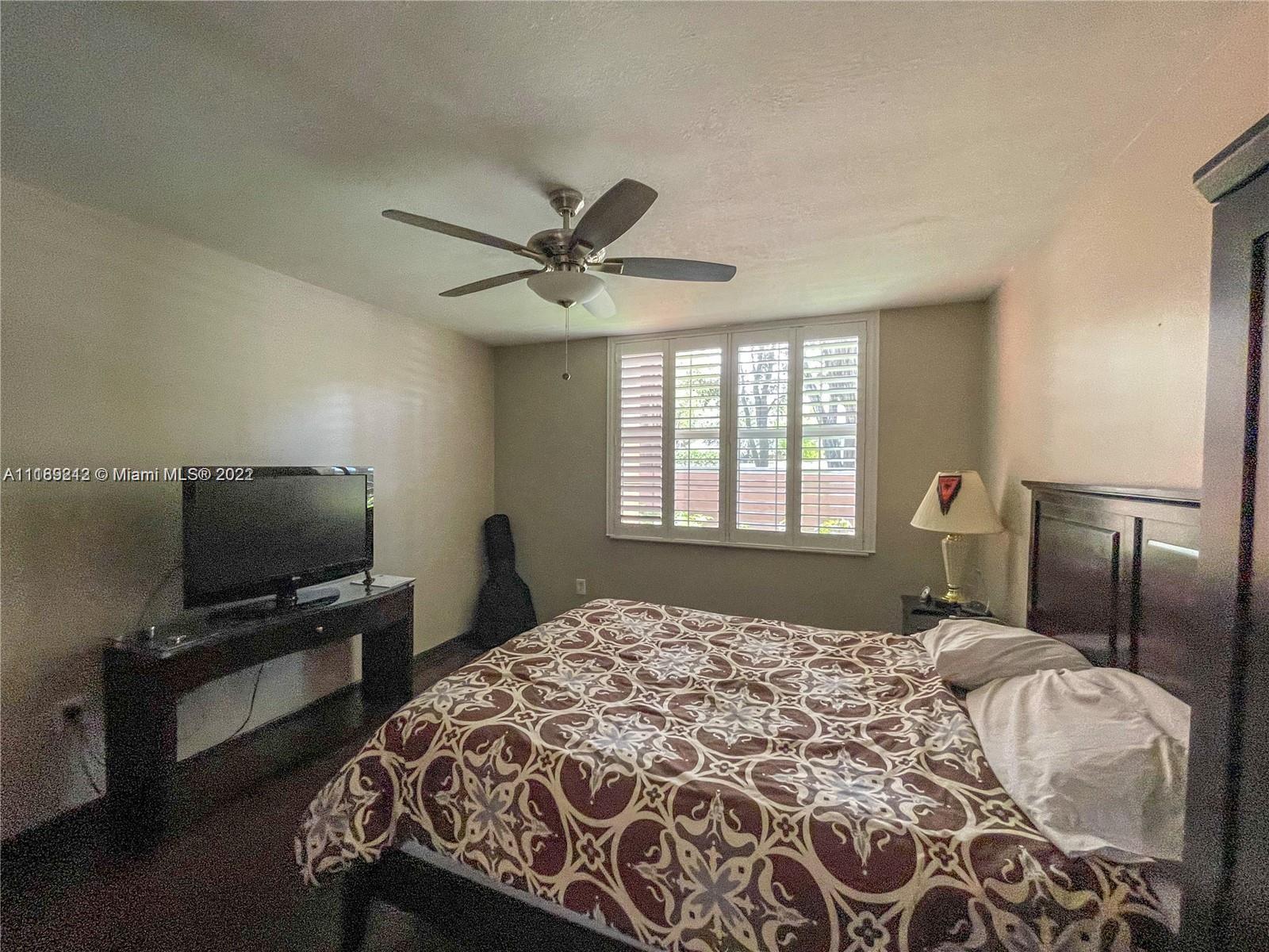 3153 Clint Moore Road, Unit 106 Boca Raton, FL 33496 - Photo 34 of 38 a bedroom with a large bed and a flat tv screen on a dresser