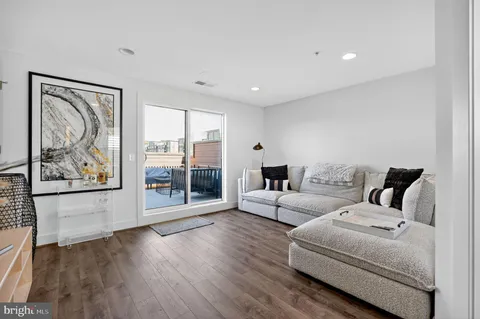 a living room with furniture large window and wooden floor