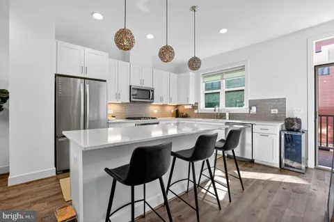 a kitchen with stainless steel appliances kitchen island granite countertop a dining table chairs stove and refrigerator