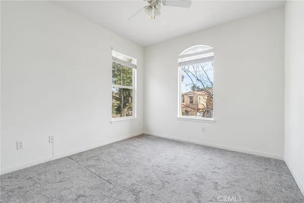 an empty room with windows and fan