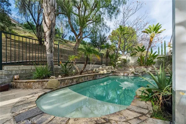 a view of a swimming pool with lawn chairs under an umbrella