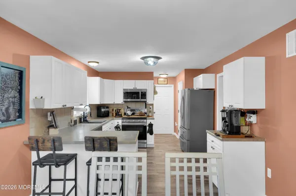 a kitchen with stainless steel appliances kitchen island granite countertop a refrigerator a stove a sink dishwasher with a dining table and chairs