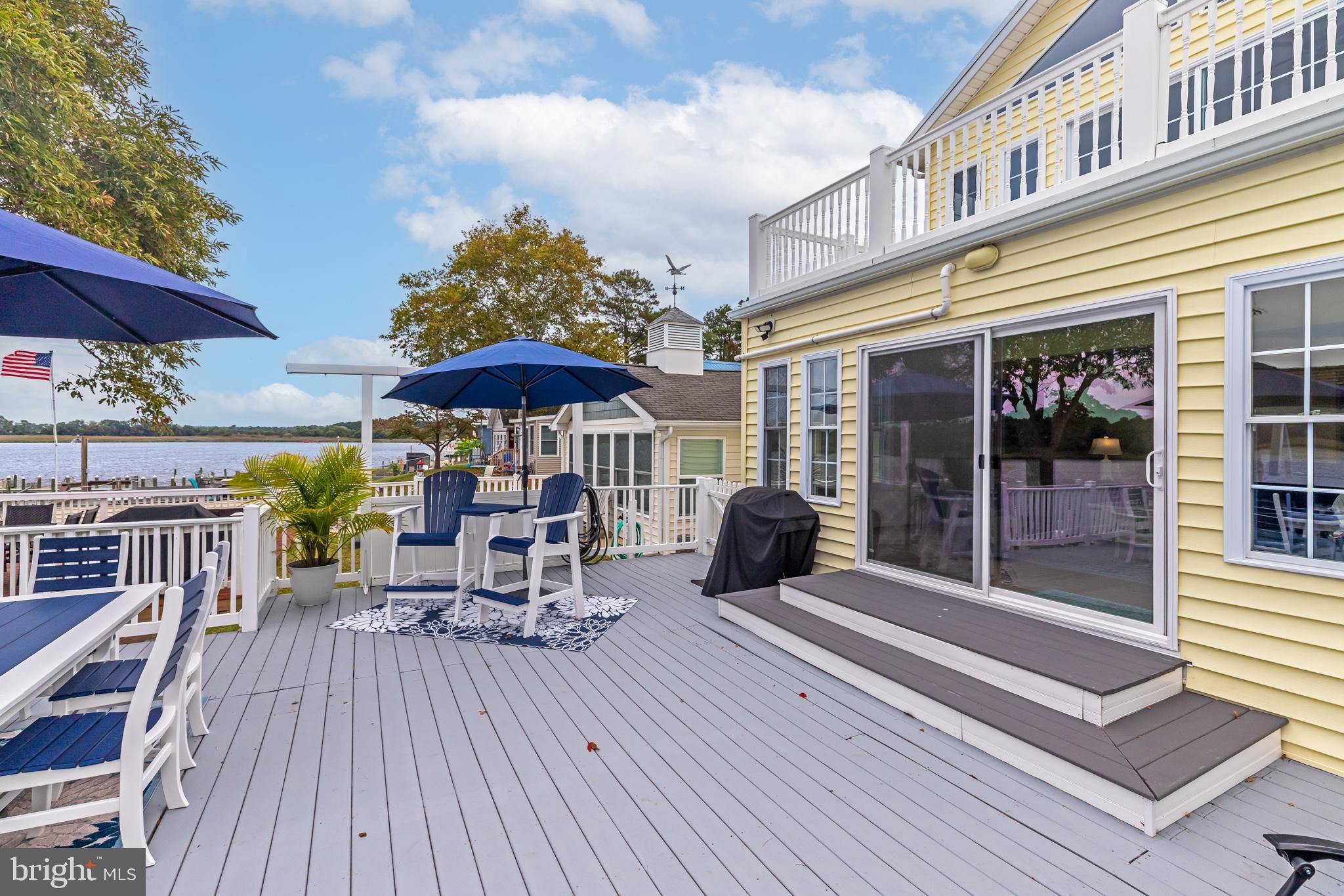 28016 Possum Point Road Millsboro, DE 19966 - Photo 55 of 70 a view of a patio with a table and chairs under an umbrella with wooden floor