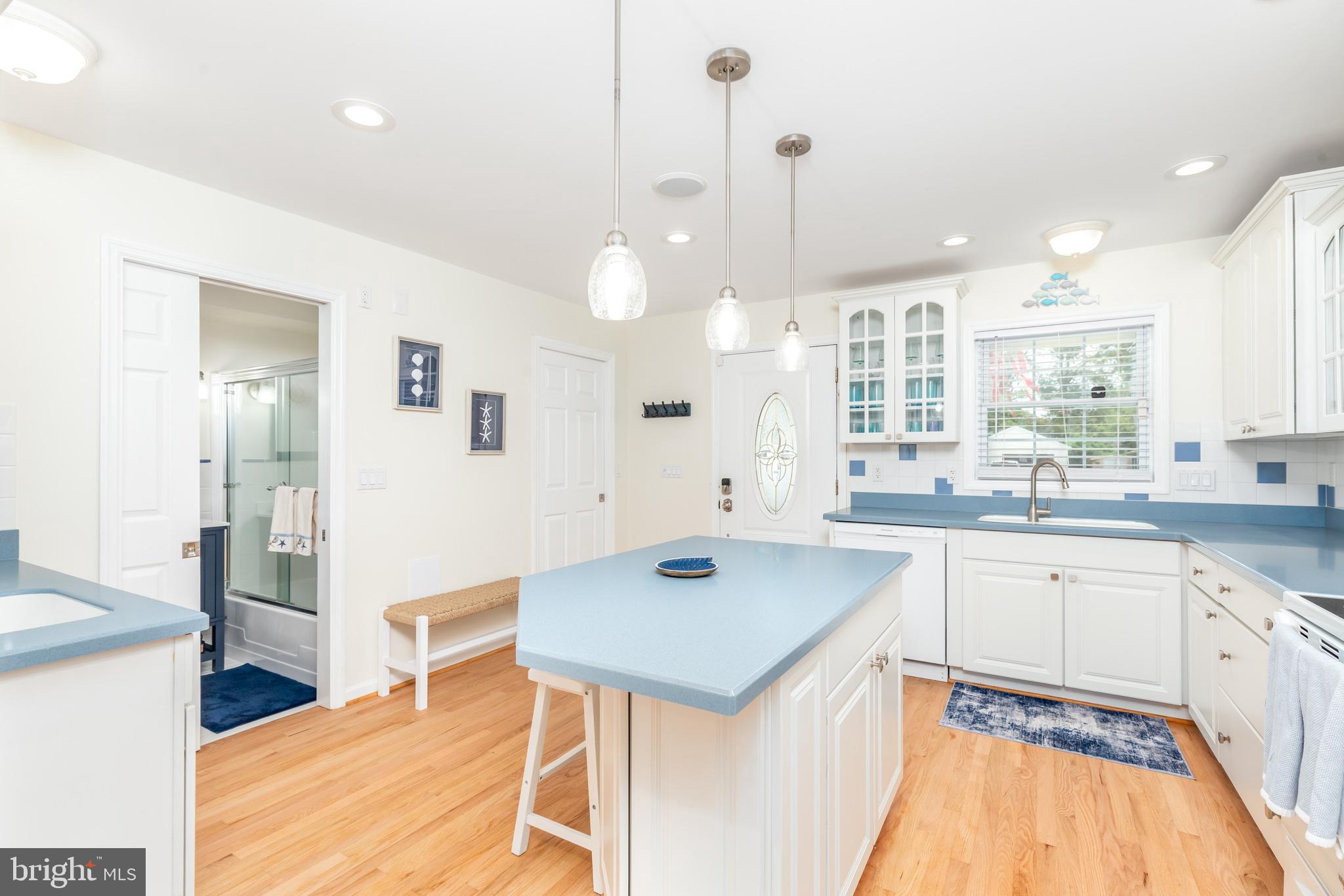 28016 Possum Point Road Millsboro, DE 19966 - Photo 9 of 70 a kitchen with a sink a stove a refrigerator and white cabinets with wooden floor