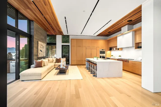 a living room with stainless steel appliances kitchen island granite countertop furniture and a wooden floor