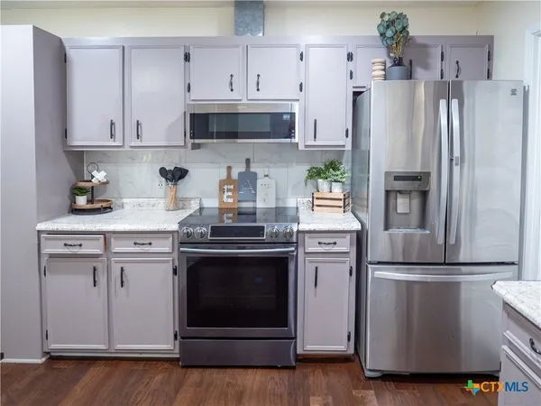a kitchen with stainless steel appliances a refrigerator stove and white cabinets