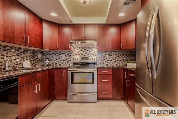 a kitchen with stainless steel appliances granite countertop wooden cabinets a stove top oven and a sink