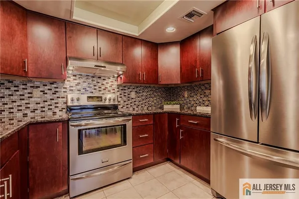 a kitchen with stainless steel appliances granite countertop wooden cabinets a refrigerator and a stove