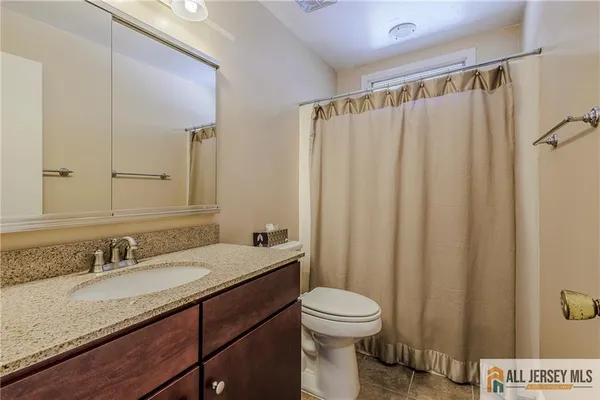 a bathroom with a granite countertop sink toilet and a mirror