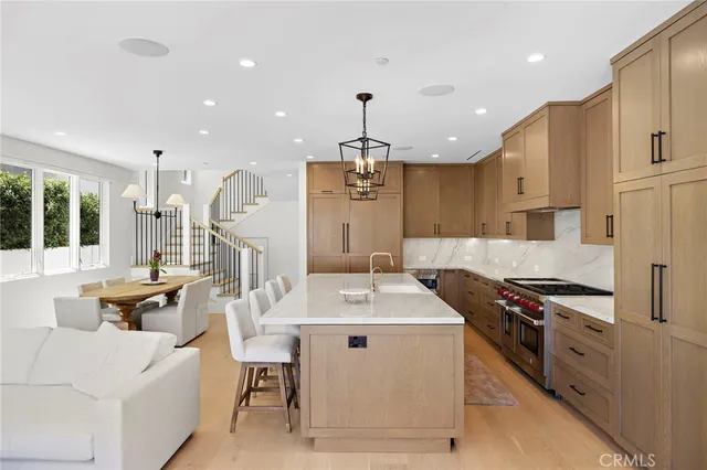 a kitchen with stainless steel appliances kitchen island granite countertop a stove a sink a refrigerator and white cabinets with wooden floor