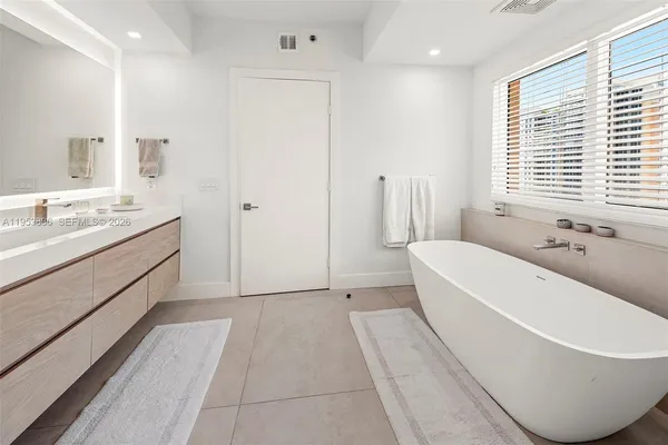a spacious bathroom with a tub sink and mirror