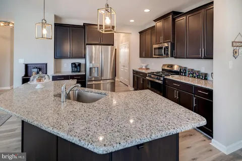 a kitchen with kitchen island granite countertop stainless steel appliances a sink stove refrigerator and cabinets