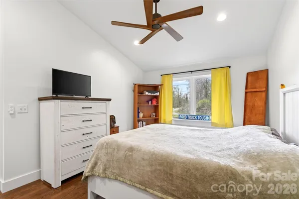 a bedroom with a bed and a flat tv screen on dresser