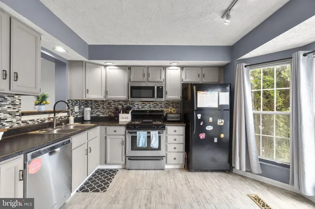 a kitchen with stainless steel appliances granite countertop a refrigerator stove and sink