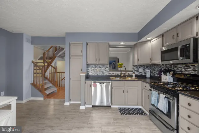 a kitchen with granite countertop a stove a sink and a microwave