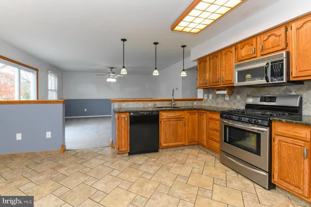 a kitchen with stainless steel appliances granite countertop a stove top oven a sink dishwasher a refrigerator and cabinets with wooden floor