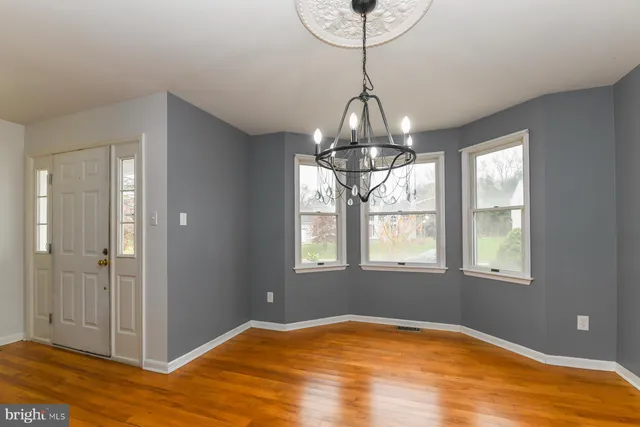 a view of a room with wooden floor staircase and a chandelier