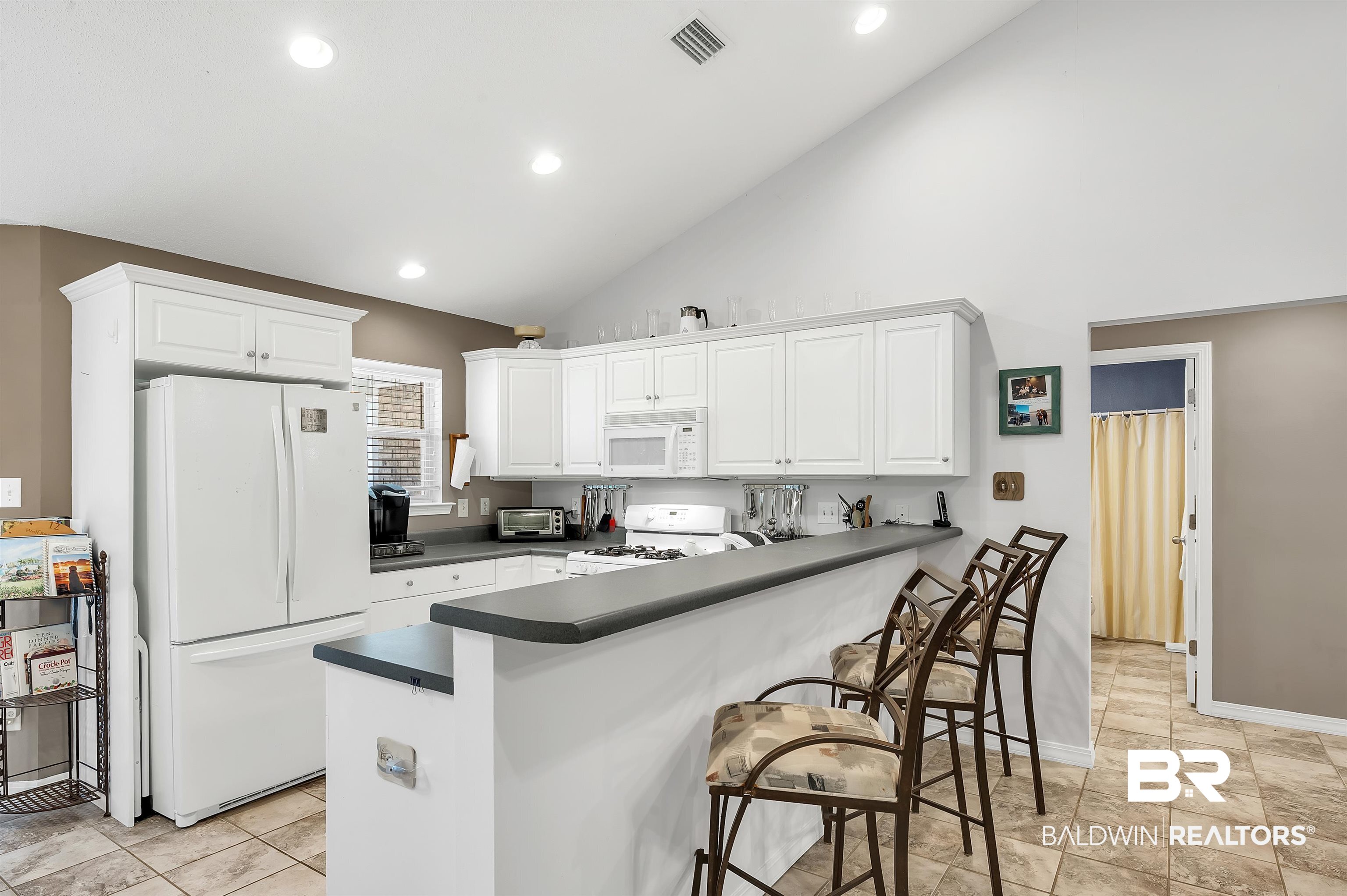 9908 Clarke Ridge Road Foley, AL 36535 - Photo 4 of 56 Kitchen with white appliances, dark countertops, visible vents, white cabinets, and a peninsula
