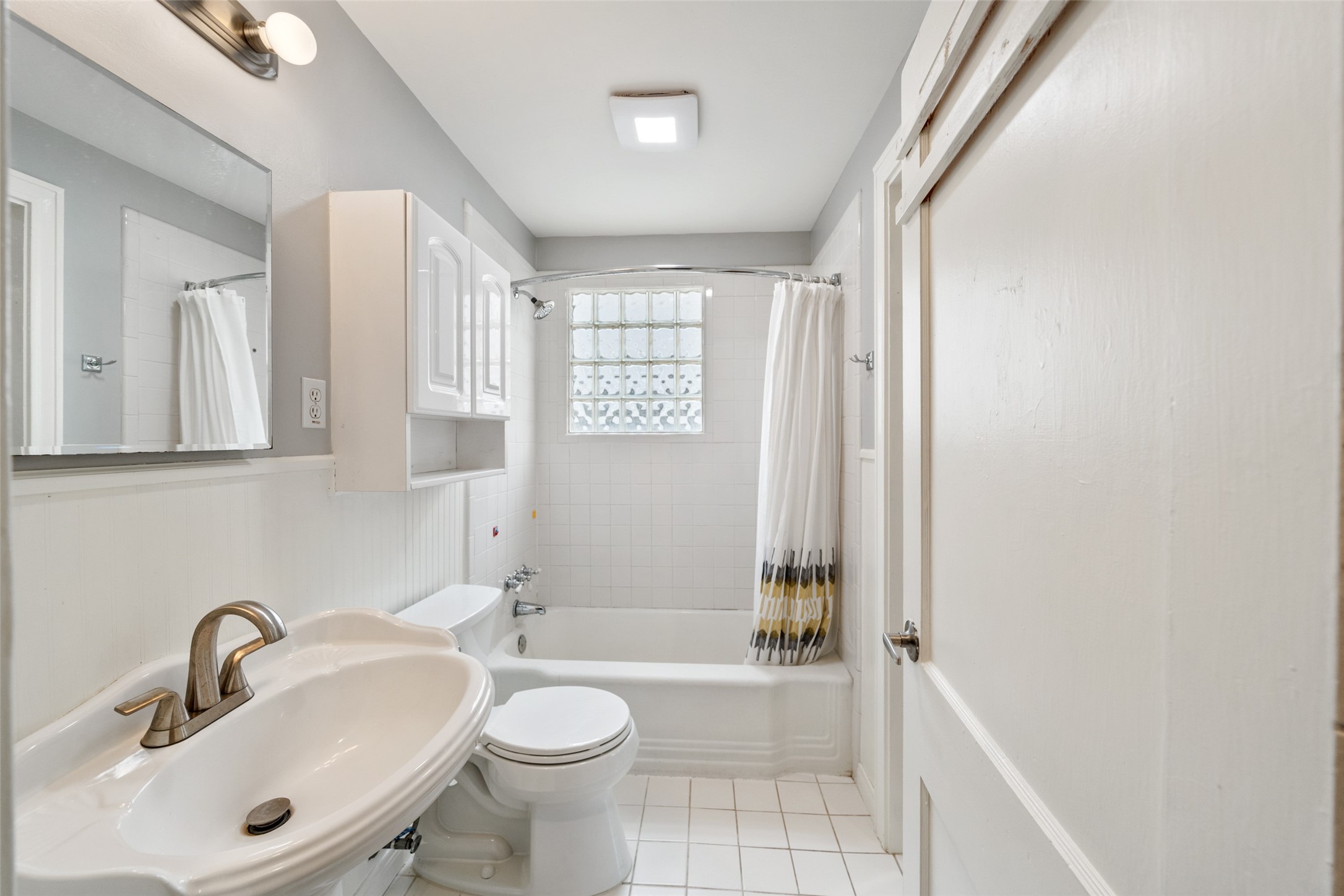 1510 Alexander Street Houston, TX 77008 - Photo 12 of 18 Original second bath — pedestal sink, glass block window, classic tub/shower combo. Clean, functional, and ready for your personal touch if you want it.