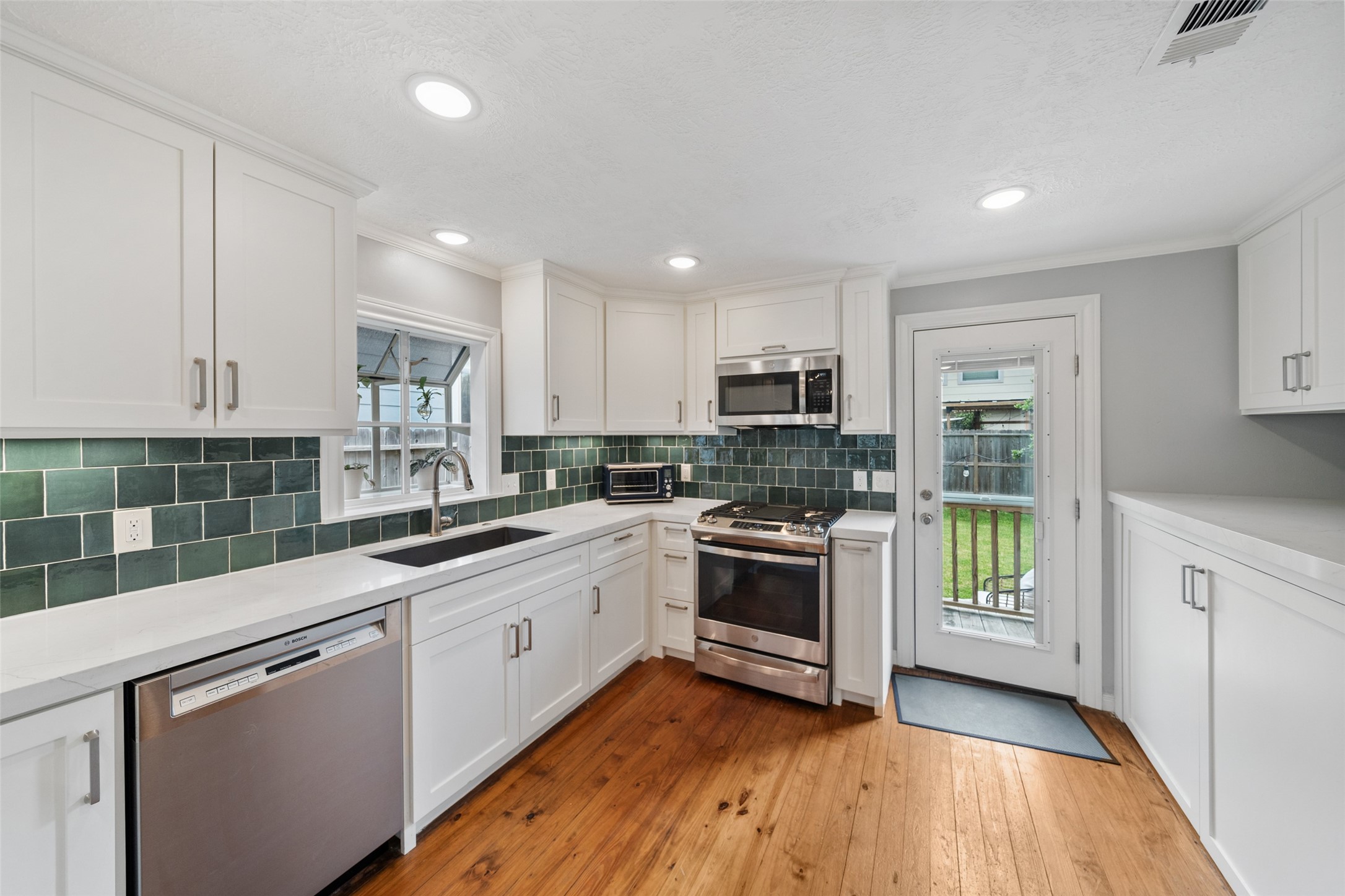 1510 Alexander Street Houston, TX 77008 - Photo 7 of 18 a kitchen with stainless steel appliances granite countertop white cabinets a sink a stove a refrigerator and microwave with wooden floor