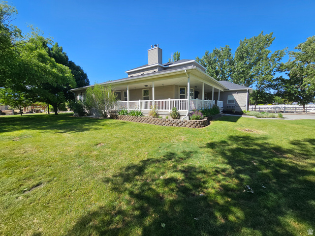 812 East Bates Cyn Road Tooele, UT 84074 - Photo 136 of 144 Expansive green lawn bordering a residence with a wraparound porch featuring white railings