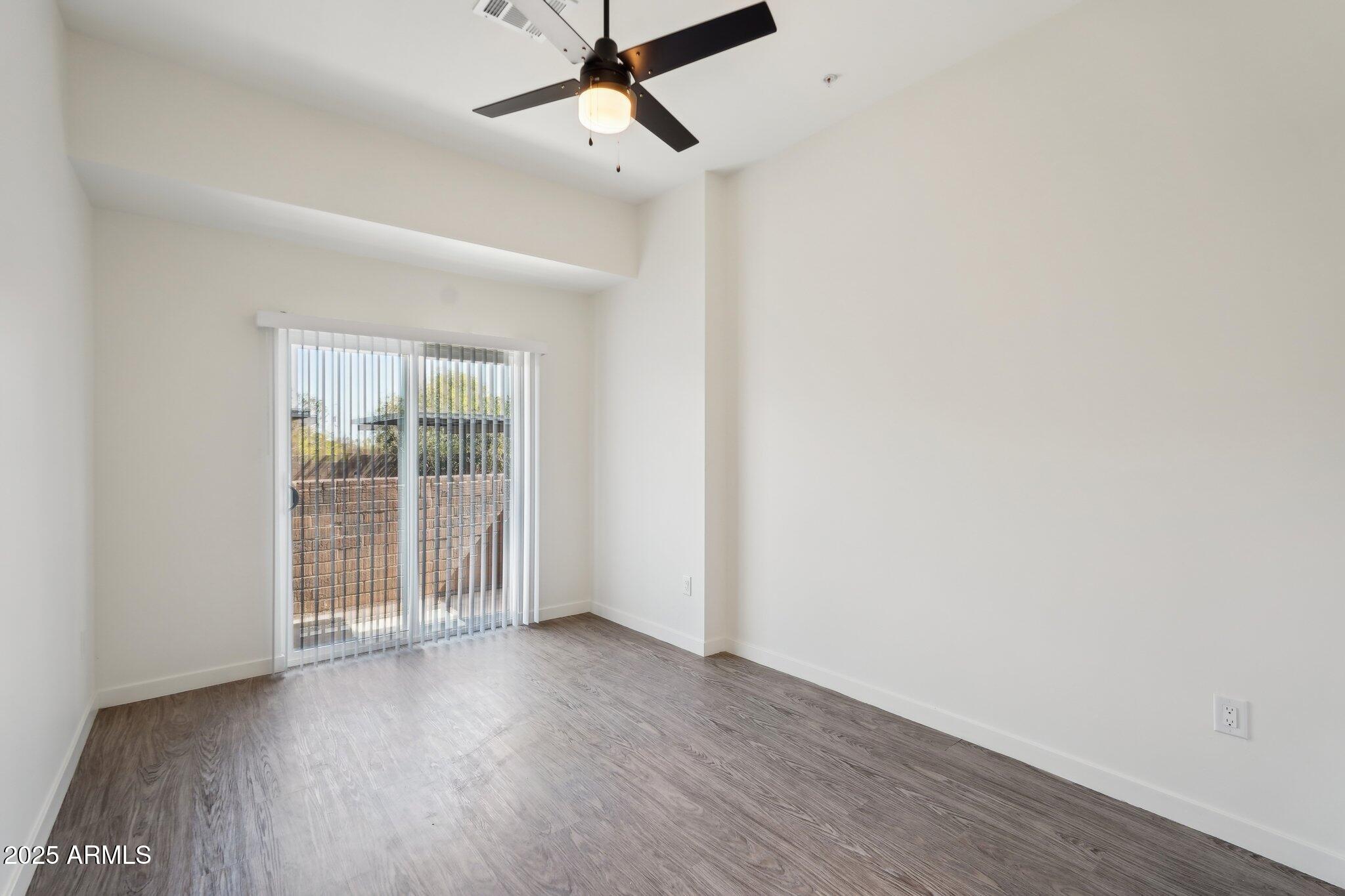 3031 West Northern Avenue, Unit 108 Phoenix, AZ 85051 - Photo 11 of 18 an empty room with wooden floor and windows