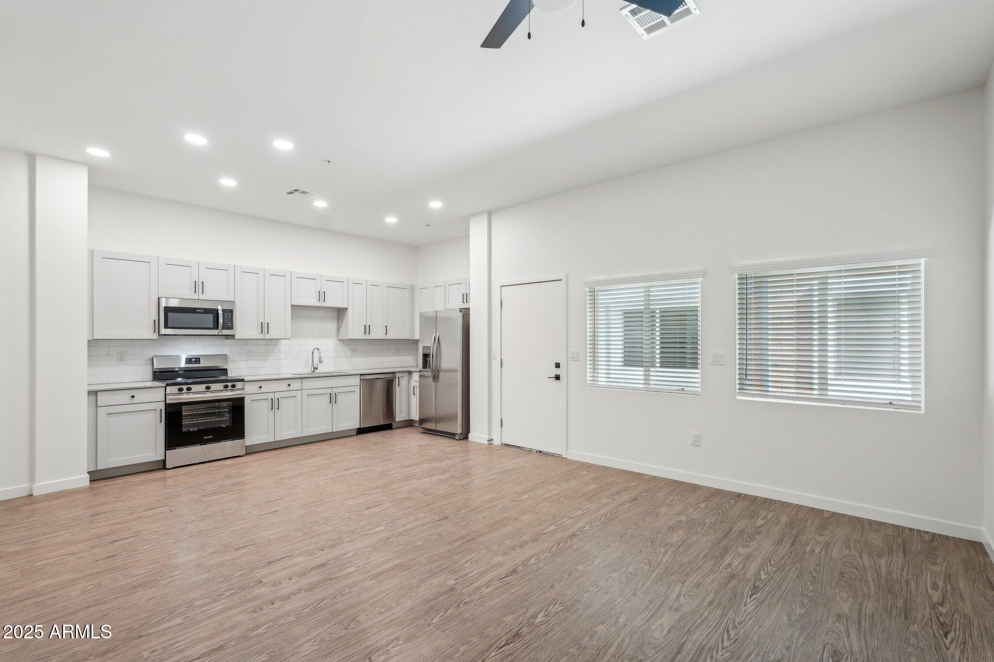 3031 West Northern Avenue, Unit 108 Phoenix, AZ 85051 - Photo 4 of 18 a large kitchen with stainless steel appliances granite countertop a stove a sink and a refrigerator